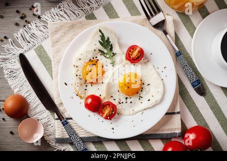 Uova fritte per colazione. Colazione sana con verdure ed erbe. Uova fritte su un piatto bianco. Servire sul tavolo. Uova fritte al mattino con coff Foto Stock