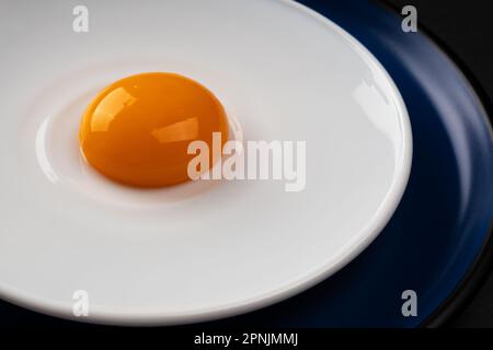 Tuorlo d'uovo sul piatto. Uova fritte astratte. Primo piano. Foto Stock