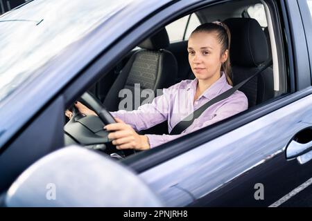 Auto alla guida. Donna felice. Tassista femminile. Noleggio o vendita di veicoli, concessionaria, autista o servizio di rideshare. Cintura di sicurezza accesa. Foto Stock