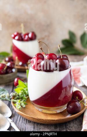 Panna cotta con gelatina di ciliegia dolce su un tavolo rustico. Dessert italiano, cucina fatta in casa. Spazio di copia. Foto Stock