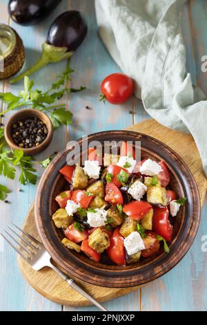 Insalata con melanzane alla griglia, pomodori e formaggio feta su un tavolo di legno rustico. Dieta sana basso carb. Foto Stock