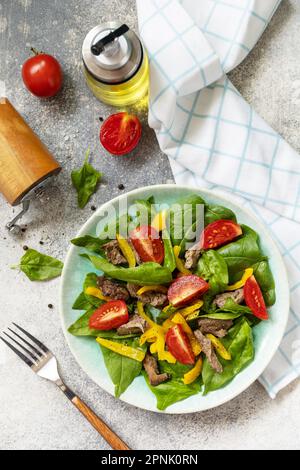 Insalata calda di spinaci giovani, fegato di pollo, pomodori e peperoni alla griglia con spezie e balsamico. Dieta sana cheto basso carb. Vista dall'alto. Foto Stock