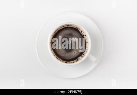 Una tazza di caffè bianca su sfondo bianco. Caffè mattutino con schiuma di caffè. Vista dall'alto. Foto Stock