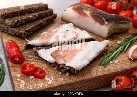 Delizioso lardo su un tagliere con verdure Foto Stock