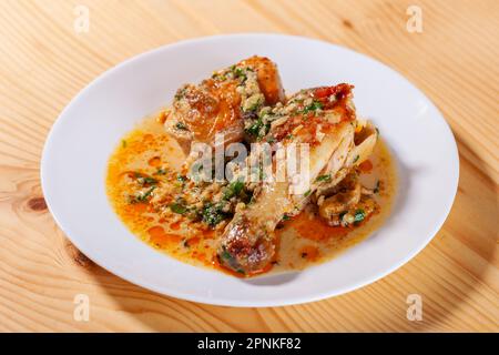 Lo Shkmeruli è un piatto tradizionale georgiano di pollo in salsa all'aglio nel piatto bianco. Cibo Foto Stock