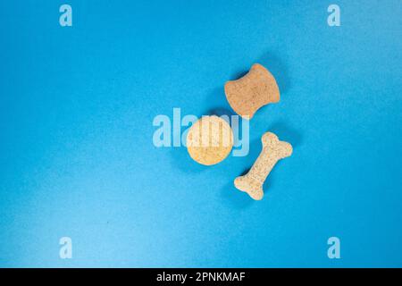 tre diversi biscotti per cani di forma isolata su sfondo blu Foto Stock