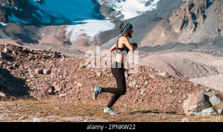 Ragazza corre sul sentiero tra le montagne innevate. Foto Stock