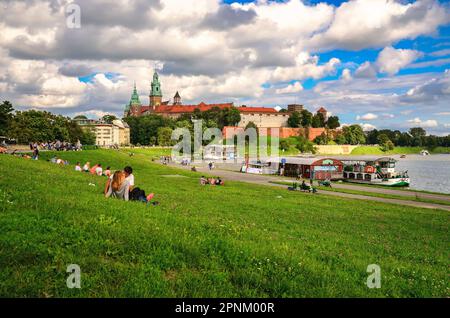 Cracovia, Polonia - 16 agosto 2014: Castello reale di Wawel a Cracovia. Turisti su prateria e barche sul fiume Vistola con il Castello reale di Wawel nel dorso Foto Stock