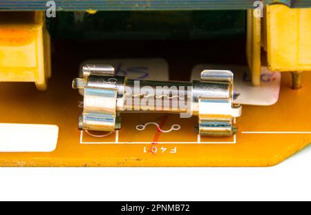 Fusibile a tubo in vetro sulla scheda elettronica degli apparecchi elettrici, componente elettronico. Foto Stock