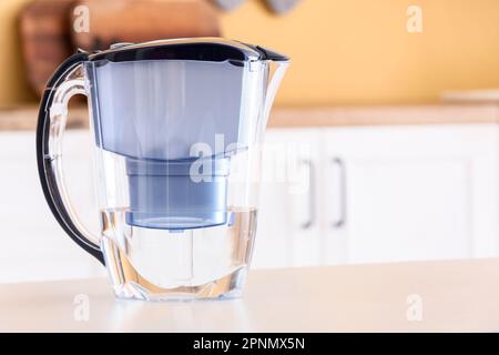 Caraffa filtro moderna con acqua sul tavolo in cucina Foto Stock