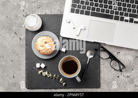 Tazza di caffè con muffin, latte, computer portatile e auricolari sullo sfondo grunge Foto Stock