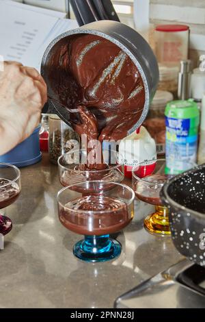 Lo chef versa la crema di cioccolato speciale di pesach con fragole e mirtilli in un recipiente speciale. Foto Stock