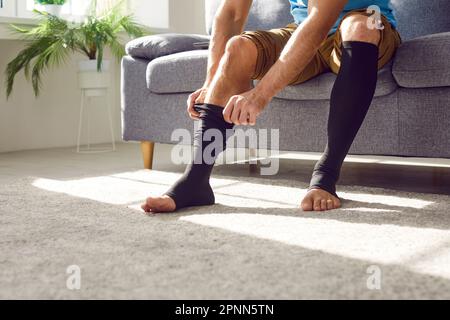 L'uomo con trombosi o malattia varicosa mette su calze di compressione allungabili Foto Stock