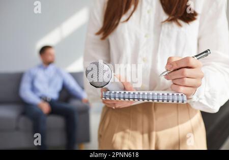 Chiuso su ripresa ritagliata di donna con microfono scrittura sul notebook Foto Stock