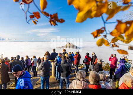 Vista del castello di Hohenzollern, sede ancestrale della dinastia principesca al sole, sotto nella valle un mare di nebbia, i visitatori guardano la natura Foto Stock