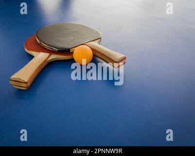 Un'immagine di una pala e palla Ping Pong appoggiata su una superficie blu vibrante Foto Stock