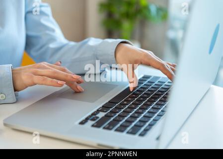 Primo piano ha girato le mani di una donna d'affari utilizzando un computer portatile a digitare sulla tastiera, cercare informazioni, navigare. Studente di sesso femminile in stage di manager Foto Stock