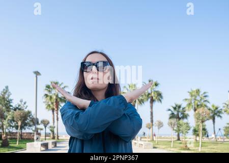 Rompere il simbolo di pregiudizio della giornata internazionale della donna. La giovane donna in occhiali da sole con braccia incrociate mostra solidarietà, impegno a invocare pregiudizi, rottura Foto Stock