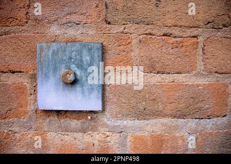 piastra di fissaggio in ferro e acciaio e bullone in una parete di mattoni rossi Foto Stock