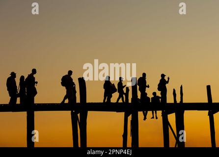 Amarapura, Myanmar - 22 novembre 2016: Persone non identificate camminano sul ponte U Bein al tramonto in Myanmar. Il ponte U Bein è il ponte in teak più lungo del Th Foto Stock