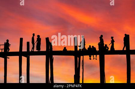 Amarapura, Myanmar - 22 novembre 2016: Persone non identificate camminano sul ponte U Bein al tramonto in Myanmar. Il ponte U Bein è il ponte in teak più lungo del Th Foto Stock