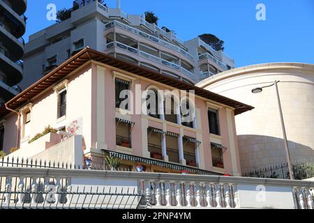 Vista ad angolo basso di una lussuosa casa rosa a due piani circondata da imponenti edifici a Monte-Carlo, Monaco, creando un accattivante contrasto Foto Stock