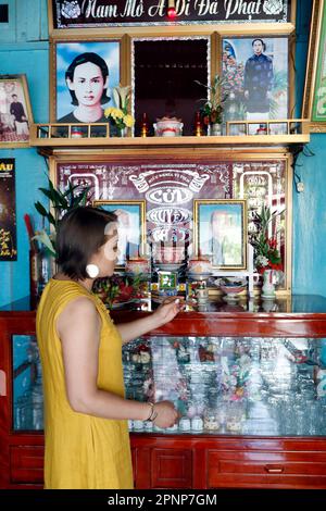 Altare antenato. La venerazione dei morti in casa. Donna che prega. Donna. Tan Chau. Vietnam. Foto Stock