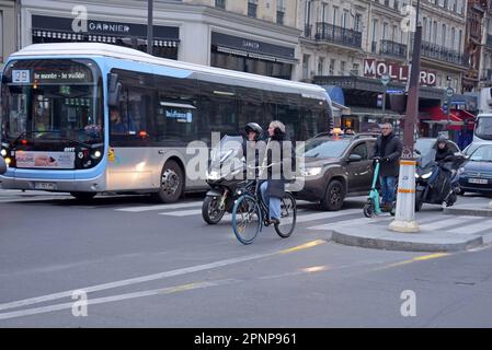 Ciclisti e scooter guidano una coda di traffico al semaforo di Parigi, che ha recentemente visto un grande aumento in bicicletta e viaggi attivi nel gennaio 2023 Foto Stock