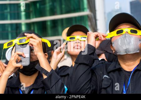 Le persone che indossano un vetro ad eclisse solare durante l'osservazione di un'eclisse solare parziale ibrida a Giacarta, Indonesia, il 20 aprile 2023. L'eclissi solare ibrido è un tipo unico di eclissi solare che sperimenta due fasi simultaneamente. (Foto di Ahmad Rajif Sidiq/INA Photo Agency/Sipa USA) Foto Stock