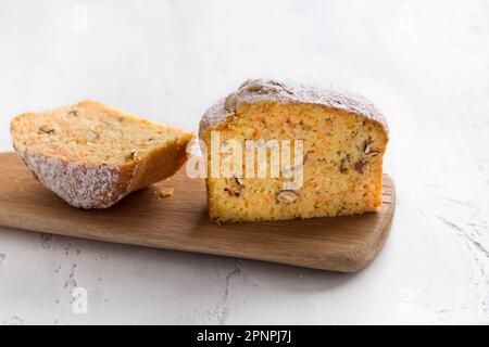Torta di semola di carote o mannik dolce appena sfornato con noci cosparse di zucchero a velo su sfondo azzurro Foto Stock