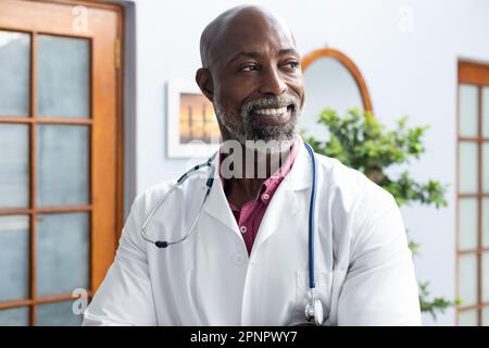 Felice medico afro-americano con stetoscopio e sorridente presso l'ufficio del medico Foto Stock