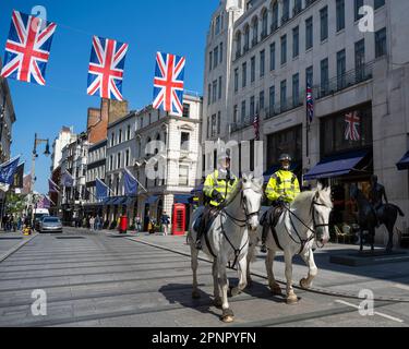 Londra, Regno Unito. 20 aprile 2023. La polizia montata passa sotto le bandiere dell'Unione installate in alto a New Bond Street prima dell'incoronazione del re Carlo III il 6 maggio. Credit: Stephen Chung / Alamy Live News Foto Stock