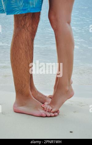Primo piano di una donna a piedi nudi in piedi sui piedi di un uomo sulla spiaggia, Giamaica Foto Stock