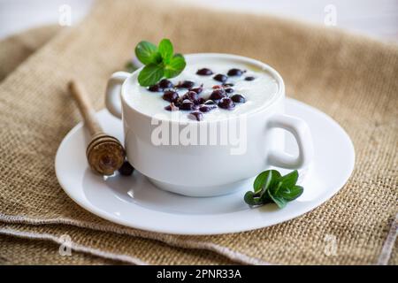 Porridge di semola cotto con bacche e miele in un piatto, su un tavolo di legno. Foto Stock