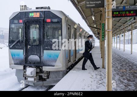 Un treno della serie JR East GV-E400 in una giornata nevosa alla stazione di Goshogawara nella prefettura di Aomori, Giappone. Foto Stock