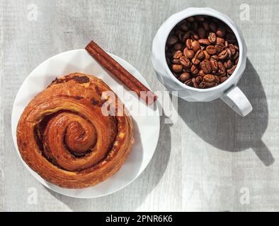 torta sul piatto bastoncino di cannella e tazza di caffè in grani sul tavolo Foto Stock