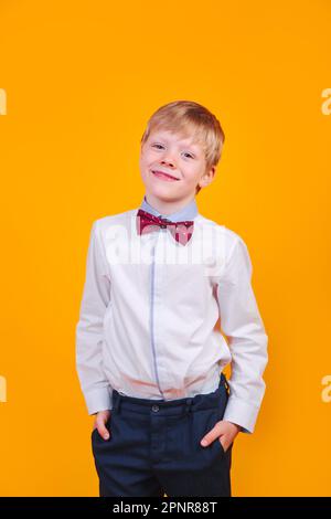 Giovane bionda elegantemente vestito che posa e sorride su sfondo giallo Foto Stock