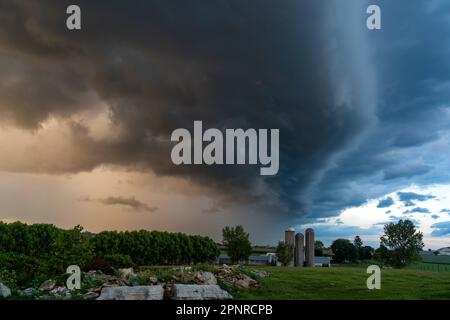 Una terribile tempesta di vista su una fattoria e il verde lussureggiante terreno agricolo della campagna in estate. Foto Stock