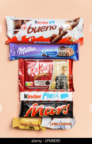 Arahal. Siviglia. Spagna. Marzo 18, 2023. Ancora vita con barrette di cioccolatini di marche diverse su sfondo arancione chiaro . Consumo eccessivo di suga Foto Stock