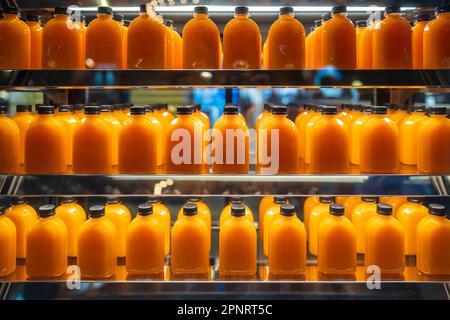 Un sacco di succo d'arancia in bottiglie sugli scaffali per la vendita in un supermercato, primo piano Foto Stock