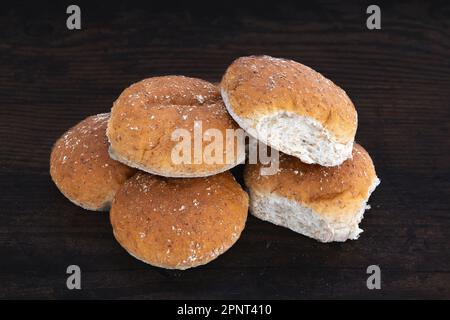 Sei BAPS o rotoli di farina d'avena marrone su un tavolo di quercia di legno scuro Foto Stock