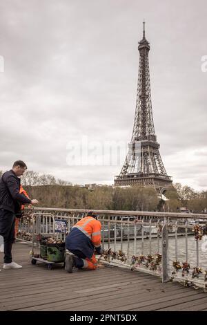 Un uomo filma sul suo smartphone come un lavoratore comunale taglia lucchetti fuori dalle ringhiere del ponte pedonale Debilly, sul fiume Senna, a Parigi, in Francia. Foto Stock
