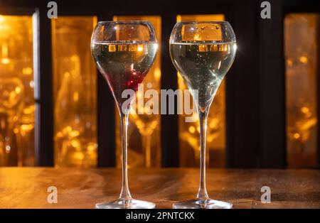 Bere il Kir Royal, cocktail francese di aperitivo a base di crema di cassis con champagne, tipicamente servito in bicchieri di tulipano serviti al bar Foto Stock