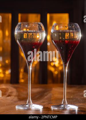 Bere il Kir Royal, cocktail francese di aperitivo a base di crema di cassis con champagne, tipicamente servito in bicchieri di tulipano serviti al bar Foto Stock