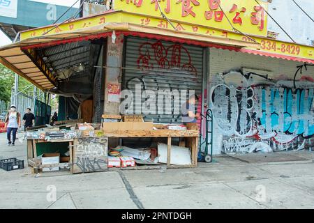 New York, NY USA - 06 27 2022: Empty Chinatown Stall con consegna persona con camion a mano Foto Stock