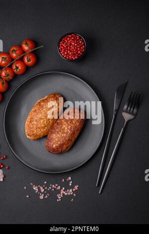 Deliziose cotolette fritte o polpette di pesce tritato con spezie ed erbe su fondo di cemento scuro Foto Stock