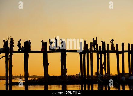 Amarapura, Myanmar - 22 novembre 2016: Persone non identificate camminano sul ponte U Bein al tramonto in Myanmar. Il ponte U Bein è il ponte in teak più lungo del Th Foto Stock