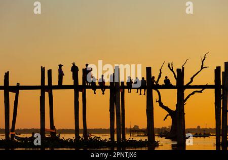 Amarapura, Myanmar - 22 novembre 2016: Persone non identificate camminano sul ponte U Bein al tramonto in Myanmar. Il ponte U Bein è il ponte in teak più lungo del Th Foto Stock