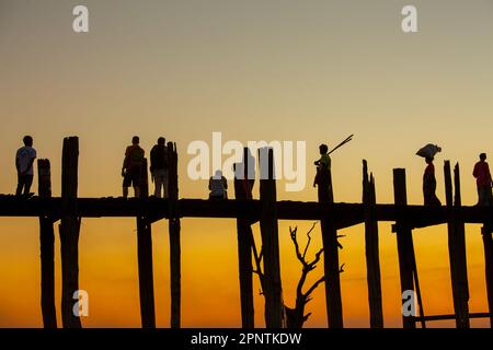 Amarapura, Myanmar - 22 novembre 2016: Persone non identificate camminano sul ponte U Bein al tramonto in Myanmar. Il ponte U Bein è il ponte in teak più lungo del Th Foto Stock