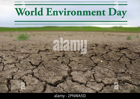 Un terreno incrinato con un campo verde sullo sfondo. Siccità acqua e clima Crisis.5 giugno giornata mondiale dell'ambiente Foto Stock